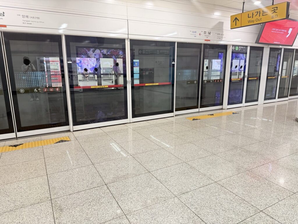 Platform screen doors at Gangnam Station on the Sinbundang Line, with the next station shown on the overhead display