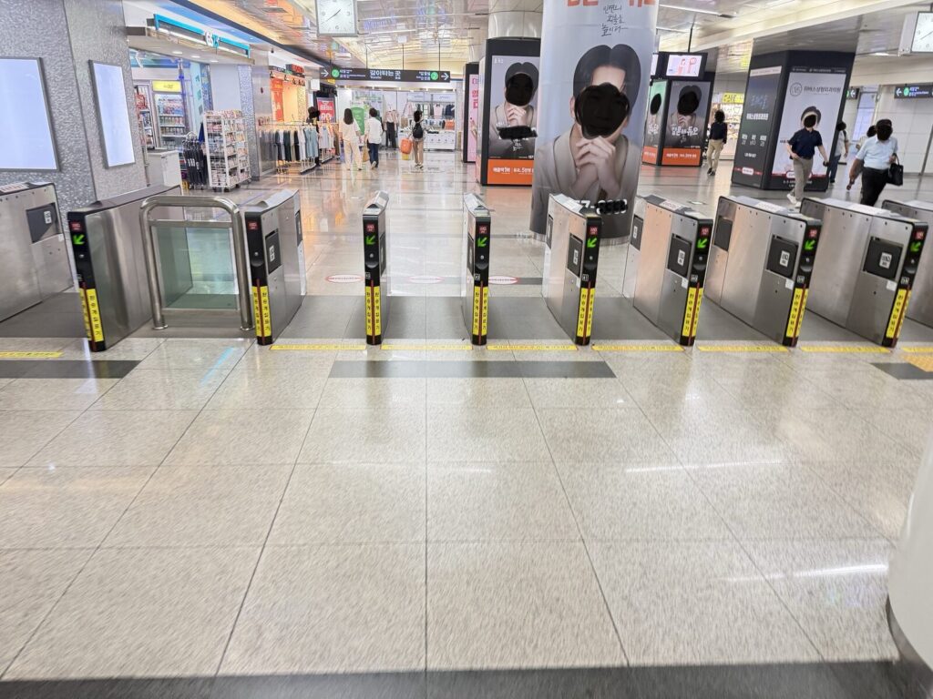 Subway turnstile gates near a GS25 convenience store inside a station concourse