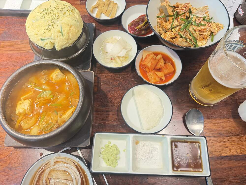 Korean BBQ table spread with soft egg souffle, stew, and side dishes at Umaju restaurant