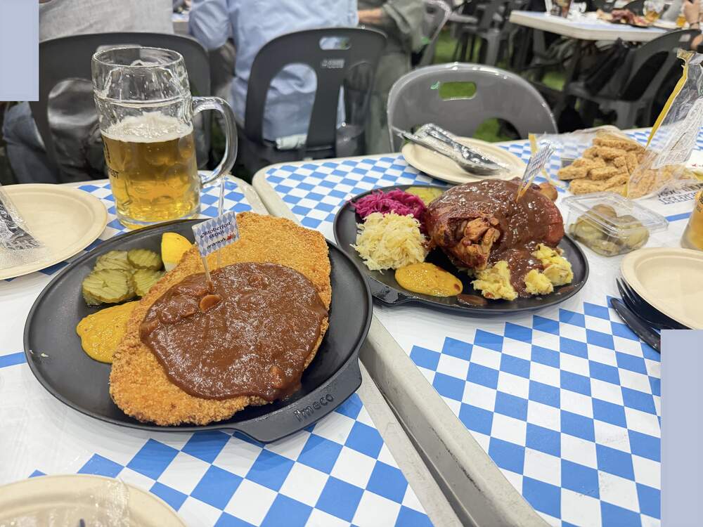 Schnitzel and Schweinshaxe pork knuckle plates on a blue and white checkered Oktoberfest tablecloth