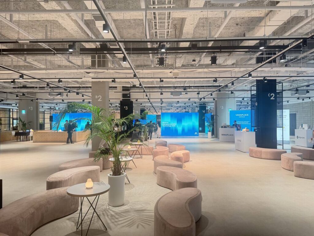 MEeT 2026 conference venue at COEX The Platz, showing lounge seating and exhibitor booths